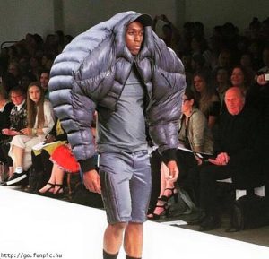 man with a large jacket walking on a fashion runway