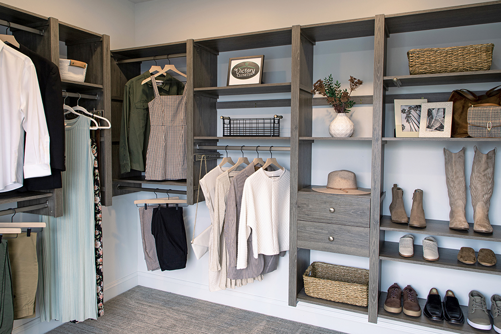 Driftwood gray-brown woodgrain corner L shaped closet with hanging clothes, shoe storage, shelves and drawers