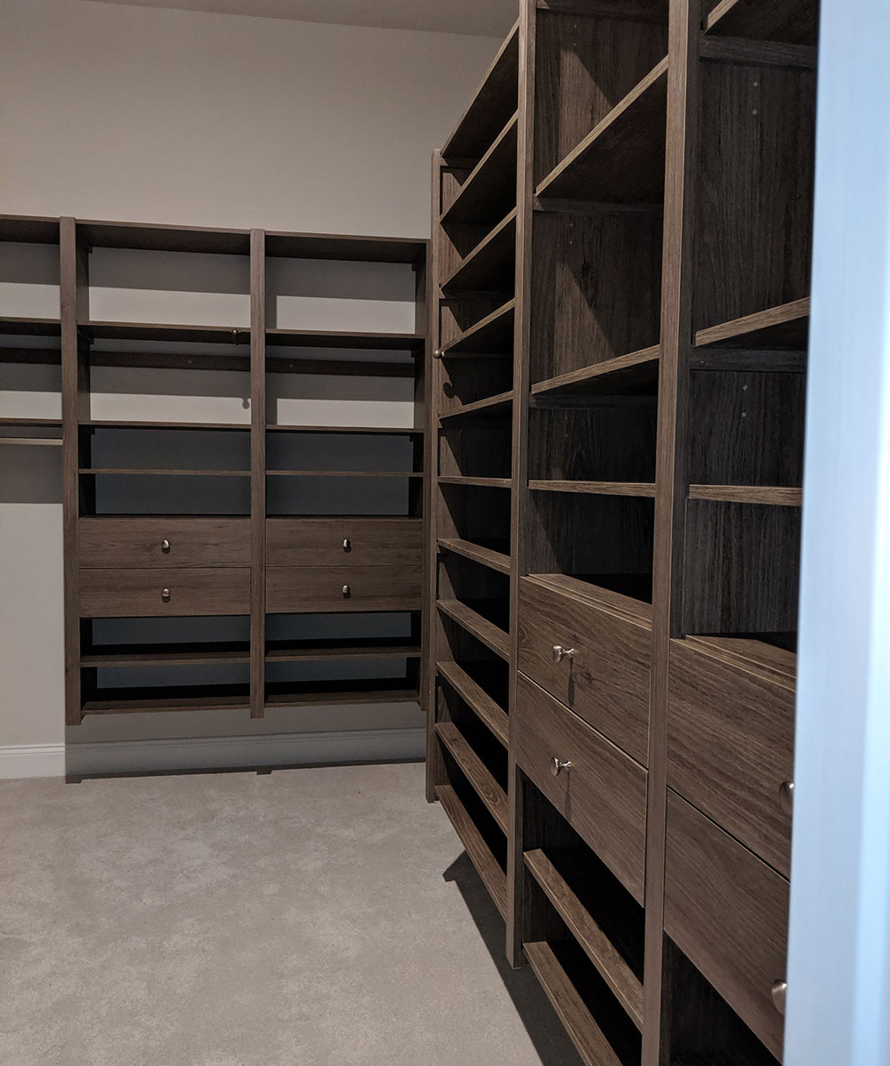 Walk In custom closet in Driftwood color showing corner with shoe shelving and 7 drawers