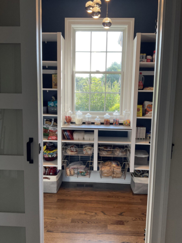 White pantry with center window with shelving below and sliding door